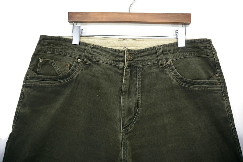 Puede incluir: Un par de pantalones vaqueros de color verde oscuro con un estilo cl&aacute;sico de cinco bolsillos.