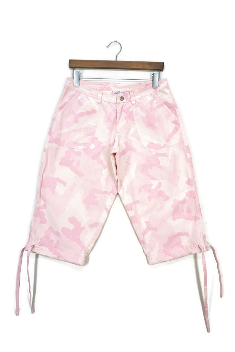 May include: Pink camouflage print cargo shorts with drawstring ties at the bottom of the legs.