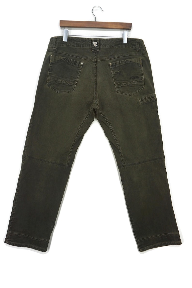 Puede incluir: Un pantal&oacute;n cargo de color verde oscuro con m&uacute;ltiples bolsillos y corte recto.