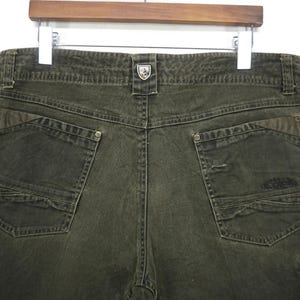 Puede incluir: Un pantal&oacute;n cargo verde oscuro con m&uacute;ltiples bolsillos y un peque&ntilde;o logotipo en la parte posterior.