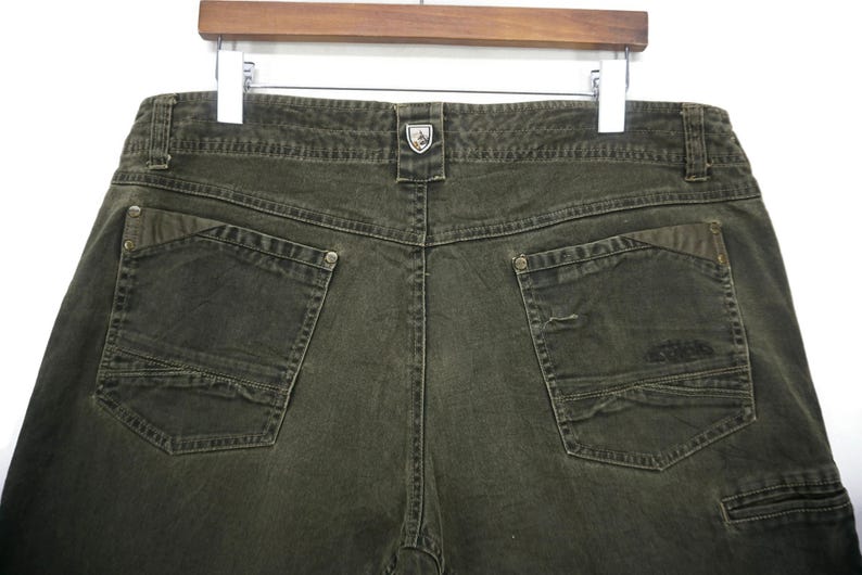 Puede incluir: Un pantal&oacute;n cargo verde oscuro con m&uacute;ltiples bolsillos y un peque&ntilde;o logotipo en la parte posterior.