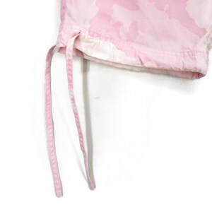 May include: Close-up of the bottom of pink camouflage pants with a drawstring.