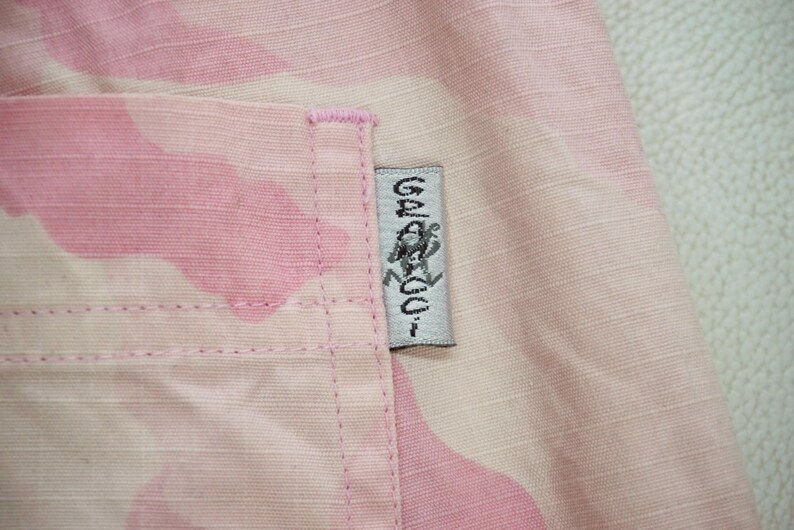 May include: Pink camouflage fabric with a white label that says "Gelato" with a graphic of a person in a circle.
