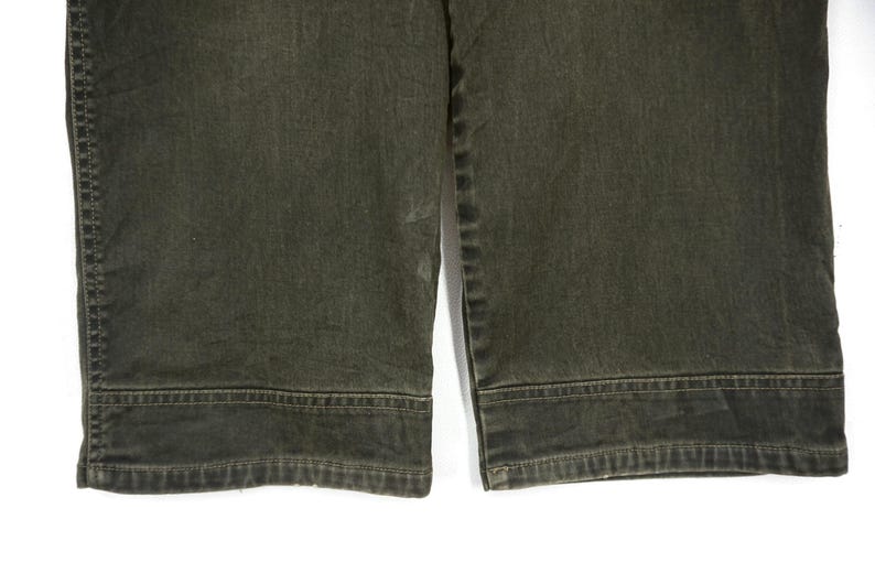 Puede incluir: Un par de pantalones vaqueros de color verde oscuro con pierna recta y dobladillo.
