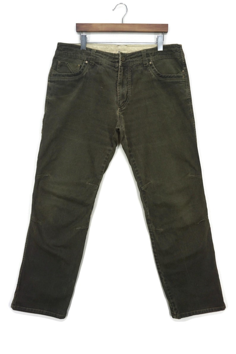 Puede incluir: Un par de pantalones vaqueros de color verde oscuro estilo cargo con m&uacute;ltiples bolsillos y cierre de bot&oacute;n.