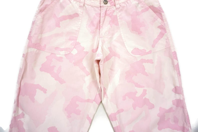 May include: Pink camouflage pants with a white background. The pants have a relaxed fit and are made of a lightweight fabric.