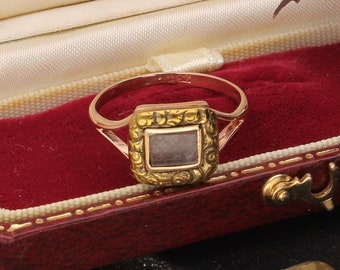 May include: A gold ring with a square-shaped stone set in a gold frame. The ring is in a red velvet box with the words "Jolly's Jewellers Mansfield - Lough 1410" on the inside of the lid.