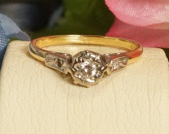 May include: A gold band ring with a single round diamond in the center and two smaller diamonds on either side. The ring is set in a white metal.