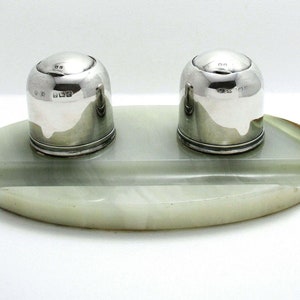 May include: A silver inkwell set with two round inkwells on a green marble base.