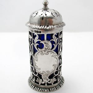 以下が含まれることがあります： 青い内装の銀色の装飾容器。容器は、装飾的な蓋とベースを備えたフィリグリーデザインです。蓋には切り抜きの模様があります。容器は、スパイスやその他の小さなアイテムを保管するためのものです。