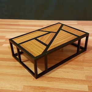 May include: A small, rectangular coffee table with a black metal frame and a wooden top. The top is made of several pieces of wood arranged in a geometric pattern.