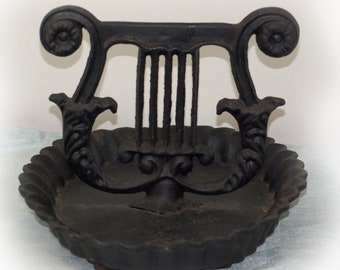 May include: A black cast iron boot scraper shaped like a lyre with a scalloped base.