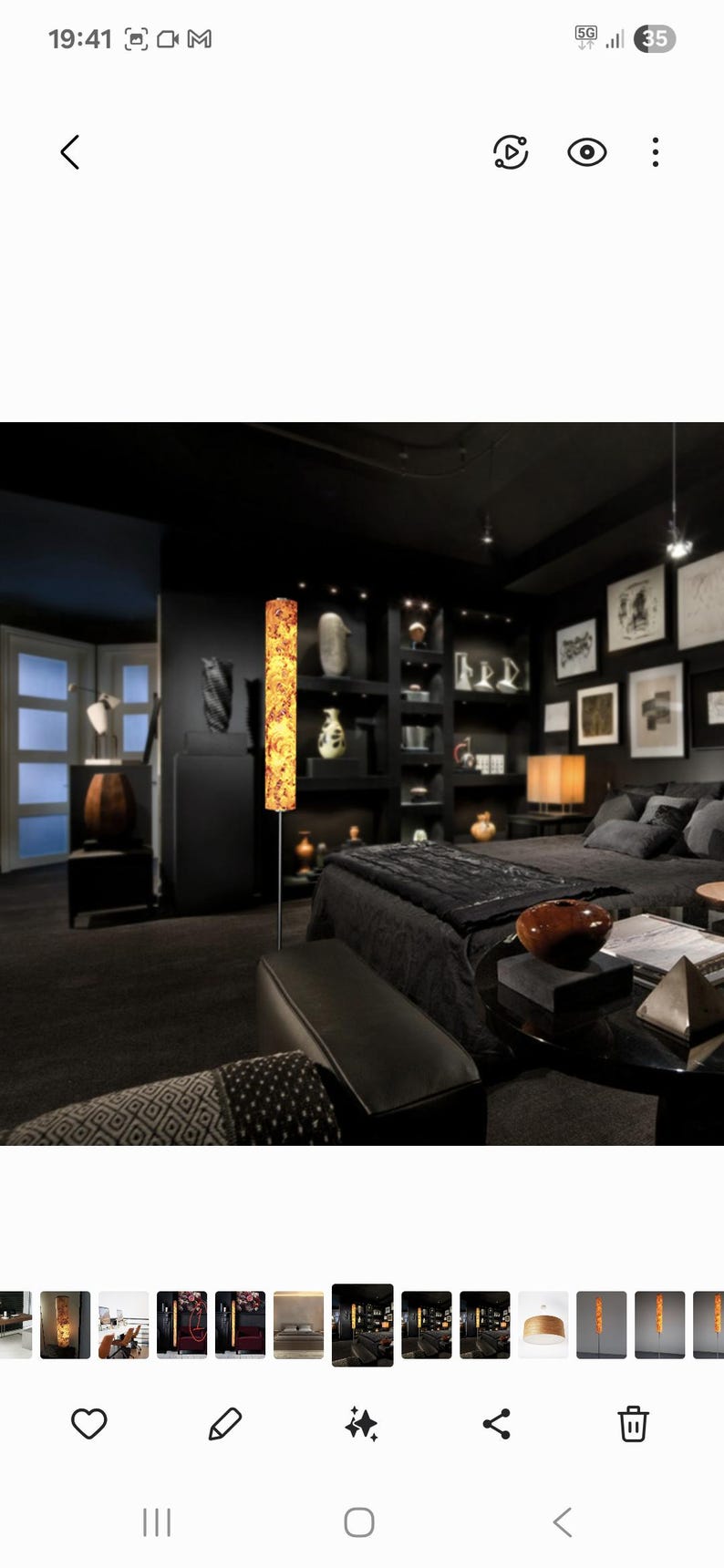 May include: A modern bedroom with black walls, furniture, and decor. A tall, decorative floor lamp with a warm, patterned shade stands out. The room includes a bed, shelves with decor, and framed artwork.