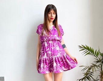 May include: A woman wearing a pink and purple floral print short-sleeved dress with a ruffled hem. She is standing on a set of stairs and wearing black sandals.