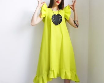 May include: A lime green dress with ruffled sleeves and a ruffled hem. The dress has a black leaf-shaped pendant necklace.