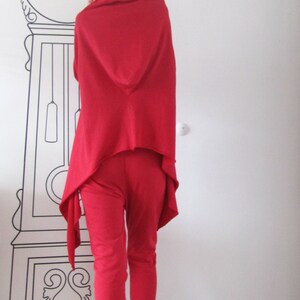 Peut inclure: Une femme portant un haut &agrave; capuche rouge et un pantalon rouge avec un bandana noir. Elle porte des baskets blanches.