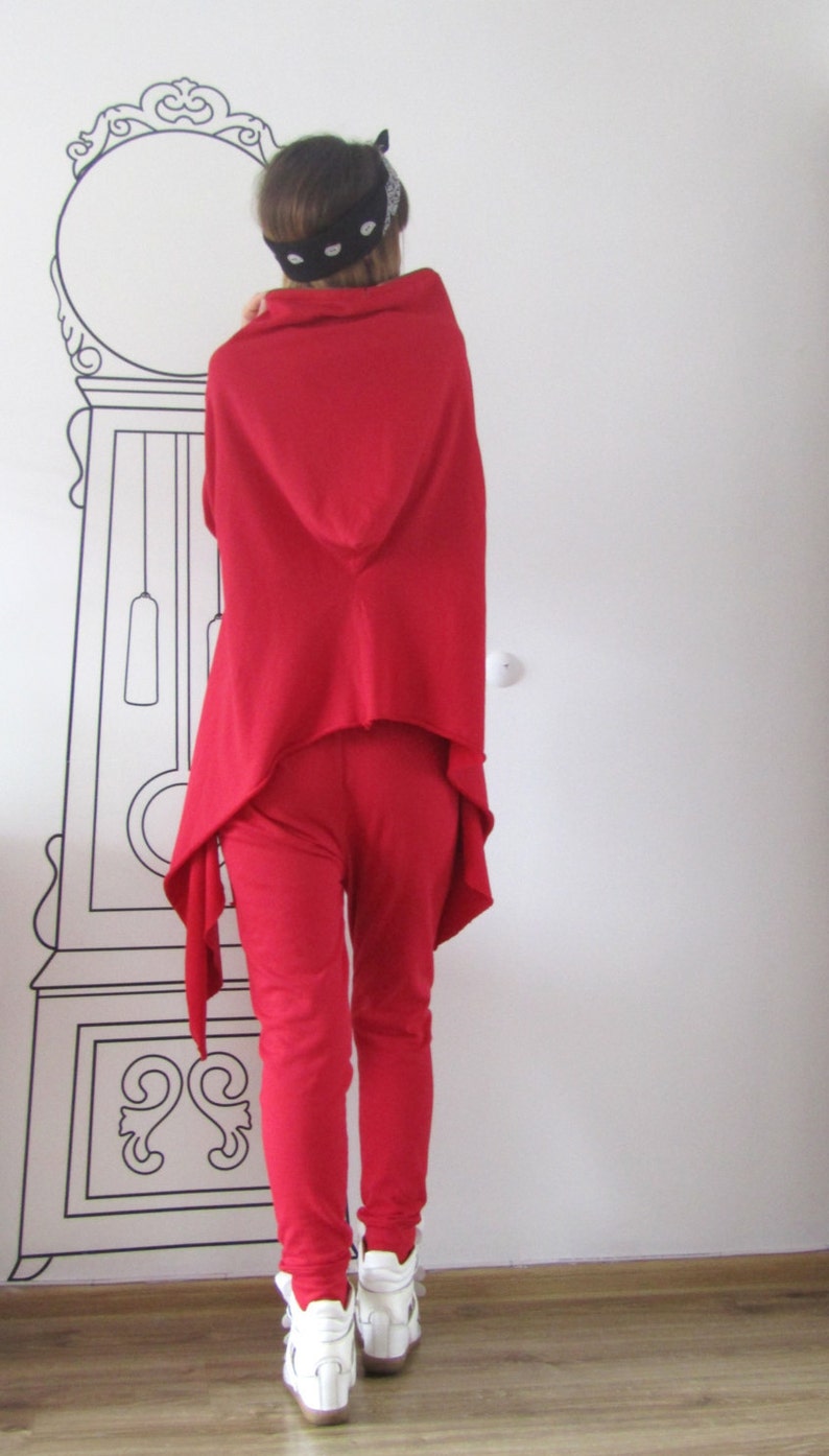 Peut inclure: Une femme portant un haut &agrave; capuche rouge et un pantalon rouge avec un bandana noir. Elle porte des baskets blanches.