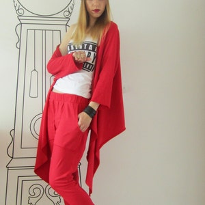 Peut inclure: Une femme portant un cardigan rouge et un pantalon rouge avec un d&eacute;bardeur blanc qui dit "Parental Advisory Explicit Content". Elle porte un bandana noir et des baskets blanches.
