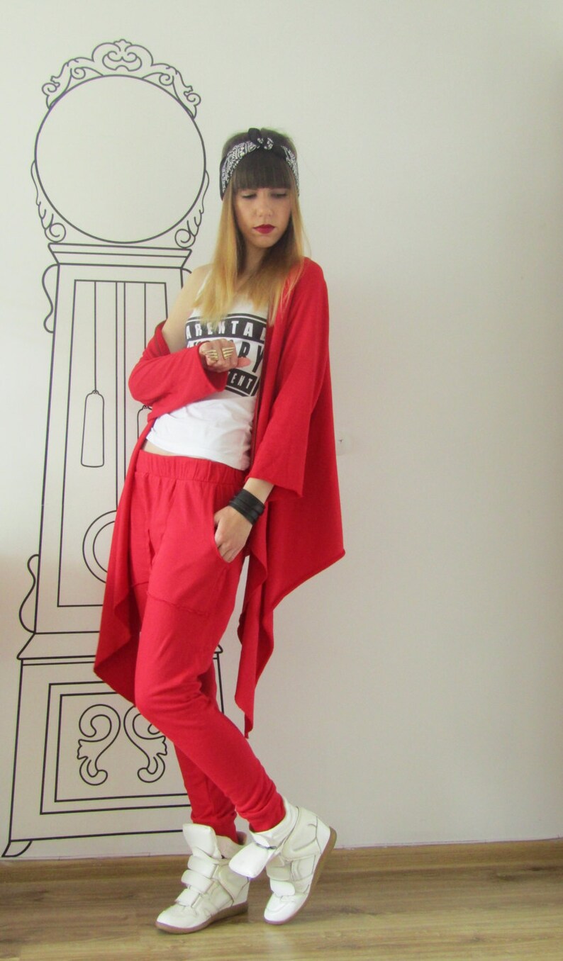 Peut inclure: Une femme portant un cardigan rouge et un pantalon rouge avec un d&eacute;bardeur blanc qui dit "Parental Advisory Explicit Content". Elle porte un bandana noir et des baskets blanches.