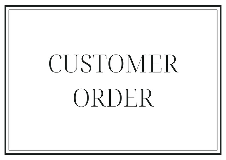 May include: A white rectangular sign with a black border displays the words "CUSTOMER ORDER" in a serif font. The text is centered and the overall design is simple and elegant.
