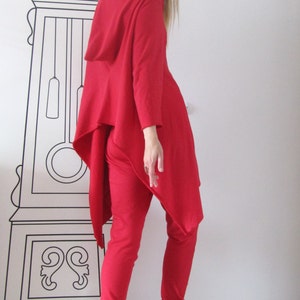 Peut inclure: Une femme portant un haut &agrave; capuche rouge et un pantalon rouge assorti. Le haut a une ourlet asym&eacute;trique long. Elle porte des baskets blanches.