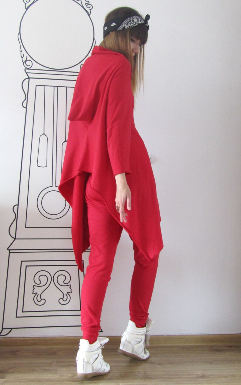 Peut inclure: Une femme portant un haut &agrave; capuche rouge et un pantalon rouge assorti. Le haut a une ourlet asym&eacute;trique long. Elle porte des baskets blanches.