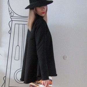 May include: A woman wearing a black fedora hat, a black long-sleeved shirt, and a colorful patterned mini skirt.