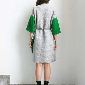 May include: A gray and green knitted cardigan with a tie belt. The cardigan has long sleeves and a relaxed fit.