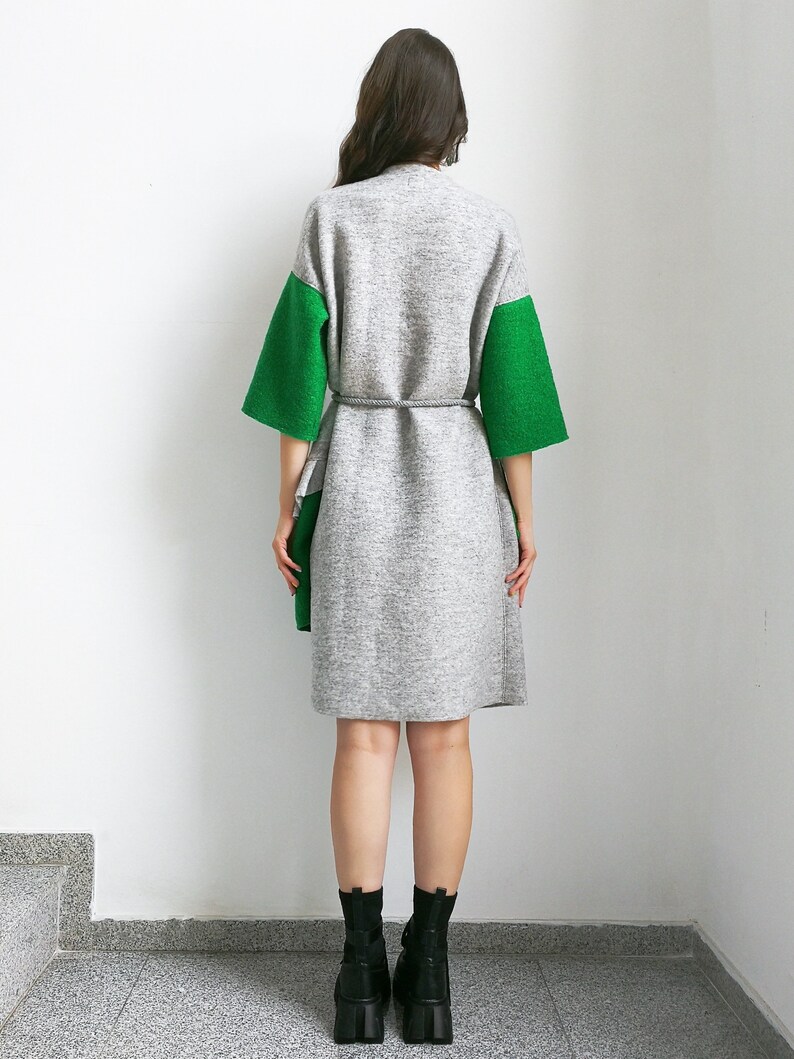 May include: A gray and green knitted cardigan with a tie belt. The cardigan has long sleeves and a relaxed fit.