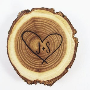 May include: A wooden slice with a heart shape carved into it. The heart has the initials "J+S" inside.