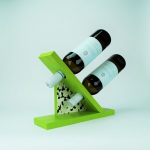 May include: A green wooden wine rack with two bottles of white wine. The rack has a black and white patterned accent.