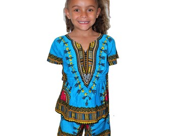 Puede incluir: Un niño o niña lleva un dashiki azul y amarillo estampado con mangas cortas y pantalones cortos a juego. El dashiki tiene cuello en V y cierre de cremallera.