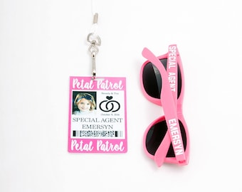 May include: A pink Special Agent badge with the text "Petal Patrol" and a photo, next to pink sunglasses with "Special Agent" printed on the arm. The badge is attached to a white lanyard.