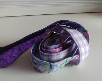 May include: A purple, floral, and white gingham patterned leash for a pet.