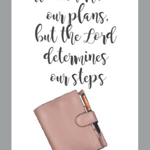 May include: A print with the text "We can make our plans, but the Lord determines our steps" and "Proverbs 16:9". A pink planner with a pen is at the bottom of the image.