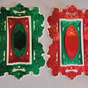 May include: Two decorative frames with ornate designs. The frame on the left is green and the frame on the right is red.