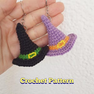 Op de afbeelding: Twee gehaakte heksenhoeden met sleutelhangers. De ene hoed is zwart met groene en gele versiering, de andere is paars met oranje en gele versiering.  "Crochet Pattern" staat onder de hoeden.
