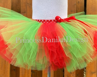 May include: A red and green tulle tutu with a red ribbon tied around the waist. The tutu is layered and fluffy, and it is perfect for a holiday party or performance.