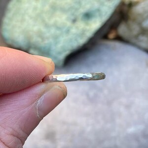 Könnte beinhalten: Ein silberner Hammerring, der an einem Finger gezeigt wird, mit einer glatten, polierten Oberfläche.