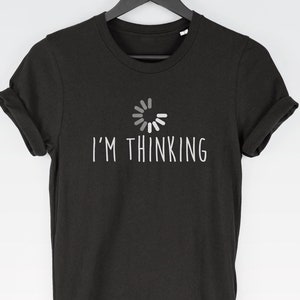 May include: A black short-sleeved t-shirt with a crew neckline and rolled sleeves. The centre of the chest features a white graphic of a circular loading icon above the white text that reads I'M THINKING in a simple, sans-serif capital font.