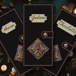 May include: Black cross-stitch book covers with names "Anne", "Gustave", and "Charlotte" in cream-colored text. Each cover has a geometric design in shades of brown. The image includes the text "pdf PATTERN" and "Heidrun Crafts".