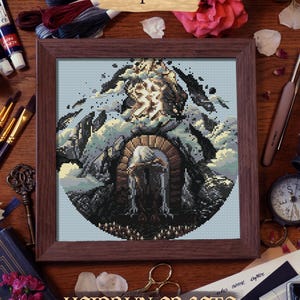 Finished cross stitch of the Paintress in silhouette against the towering monolith, with glowing highlights and dramatic framing.