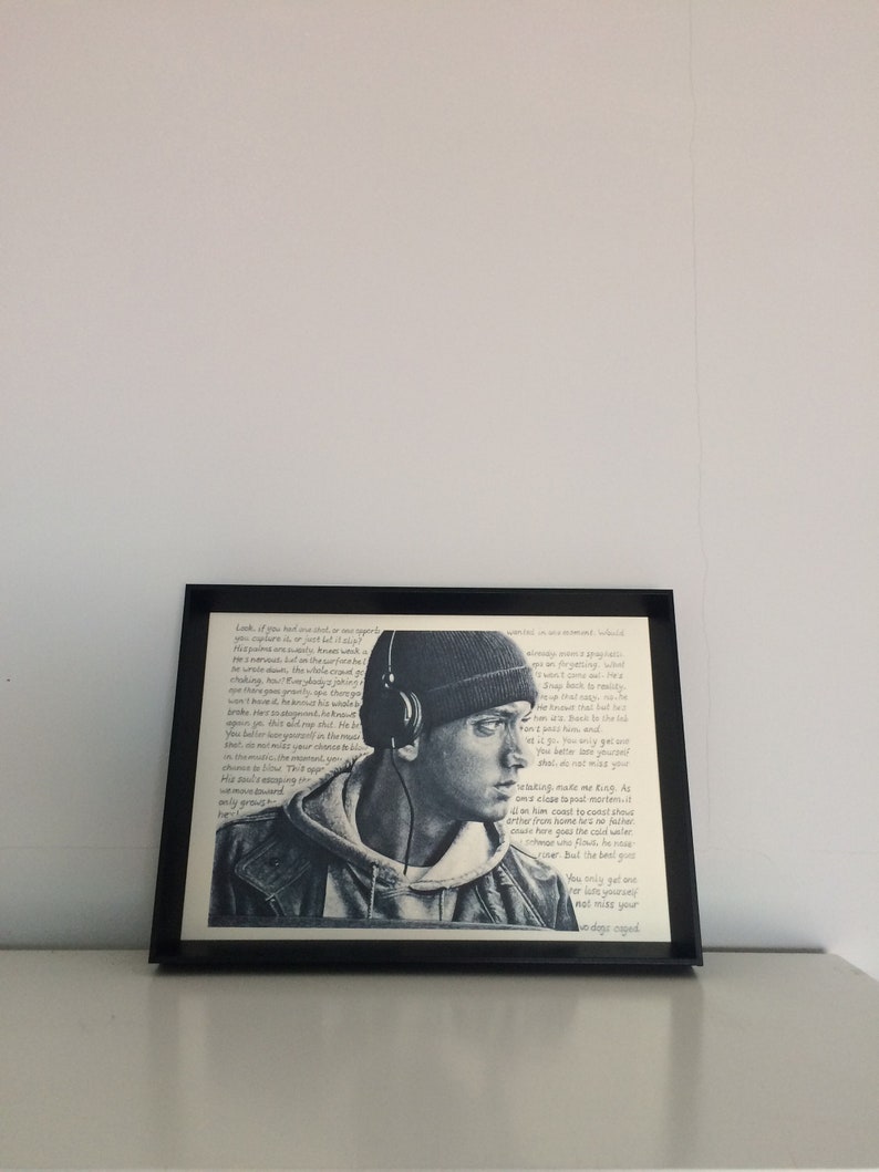 May include: A black and white framed print of a man wearing a black beanie and headphones. The print features text in a handwritten style. The text reads "Look if you feel one soul or one spirit..."