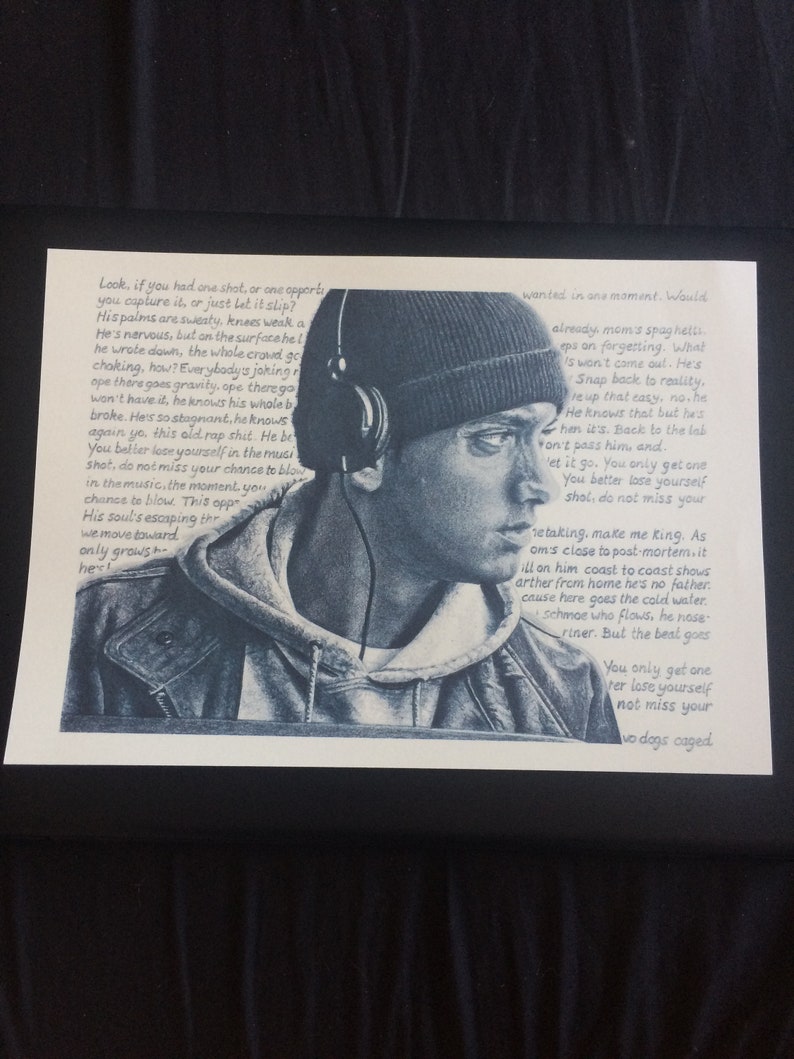 May include: A black and white photograph of a man wearing a black beanie and headphones. The man is looking to the right and has a serious expression on his face. The photo is printed on a white background. The text "Look, if you had one shot, or one opportunity..." is written in black ink on the left side of the photo. The text "...wanted in one moment. Would already mom's spaghetti..." is written in black ink on the right side of the photo.