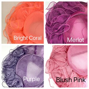 May include: Four different colored hats made of ruffled fabric. The hats are in the colors bright coral, merlot, purple, and blush pink.
