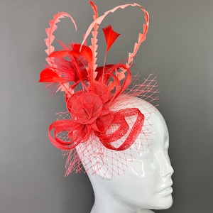 May include: A red and pink feather and net fascinator with a large red bow.