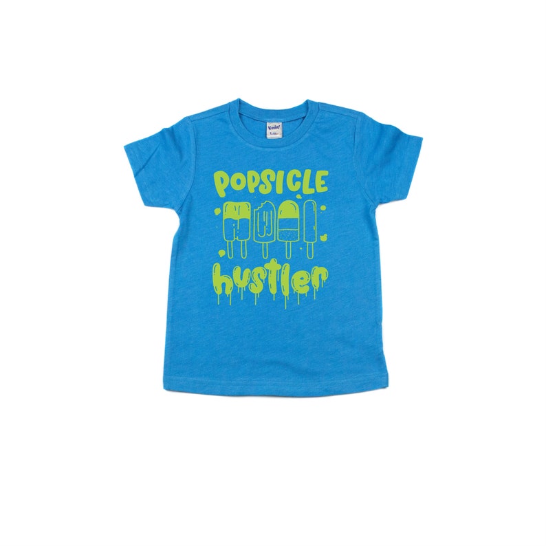 May include: A turquoise blue t-shirt with a lime green graphic of popsicles and the text "Popsicle Hustler".