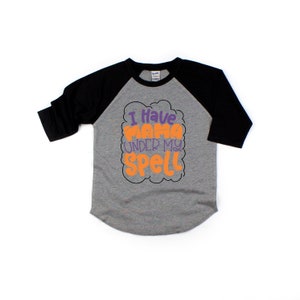 May include: A grey and black baseball tee shirt with the text "I have mama under my spell" in orange and purple lettering.