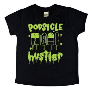 May include: Black t-shirt with a green graphic of popsicles and the text "Popsicle Hustler".