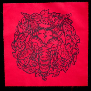 May include: Black and white illustration of a creature's head with a detailed design, surrounded by leaves on a red background.